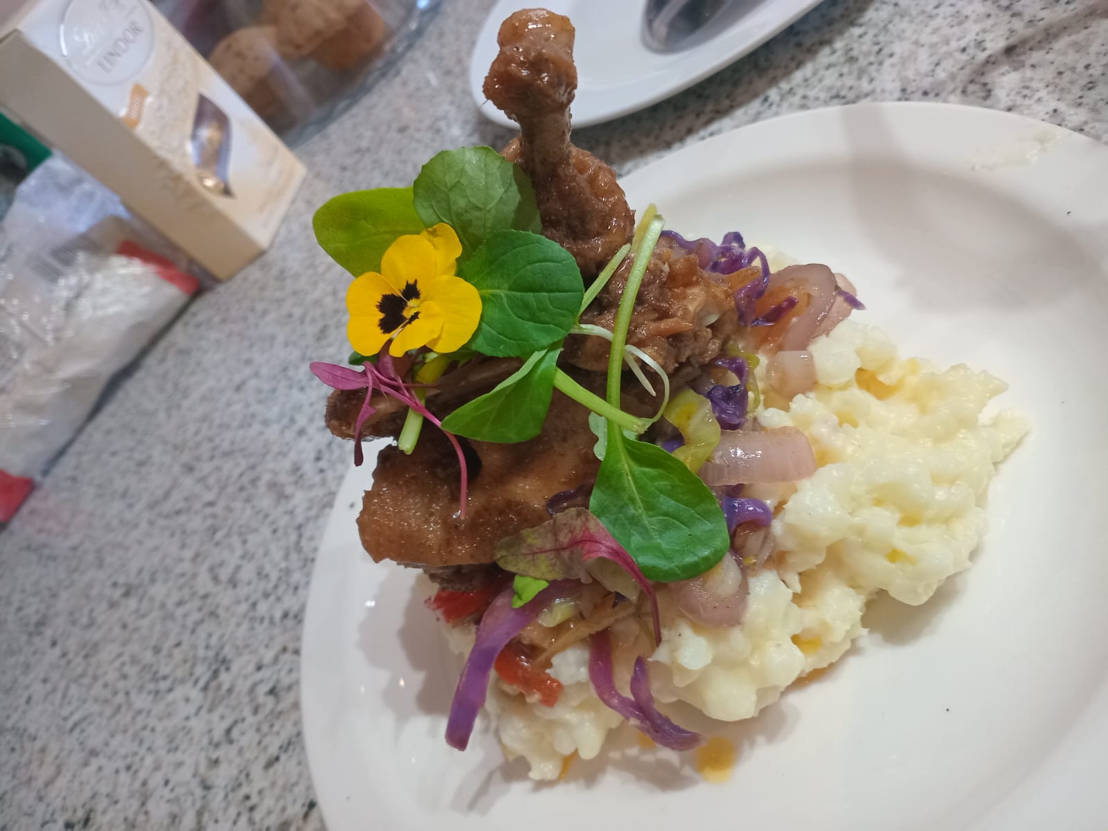 Fine dining chicken leg on pearl wheat with edible pansy flower